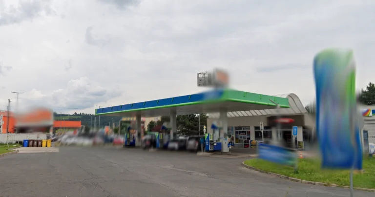 Toto je fotografia čerpacej stanice OMV v Spišskej Novej Vsi v Košickom kraji. Napravo dominuje veľký modro-zelený pylón s logom OMV na vrchu a pod ním logom pre Viva. Na pylóne je tiež nápis „MAXX Motion“ s cenami nafty a benzínu „19.5“ a „9.5“. Ostatnú časť obrázka zaberá areál čerpacej stanice. Veľký zelený prístrešok s modrým lemom s logom a nápisom OMV pokrýva stojany na výdaj pohonných hmôt. Pod prístreškom je zaparkovaných niekoľko áut a vidno niekoľko výdajných stojanov. Za čerpacou stanicou vidno veľkú oranžovo-hnedú budovu s nápisom OBI. K areálu vedie príjazdová cesta, pri ktorej je bilbord s reklamou na OMV. Pozadie tvoria stromy a zatiahnutejšia obloha.