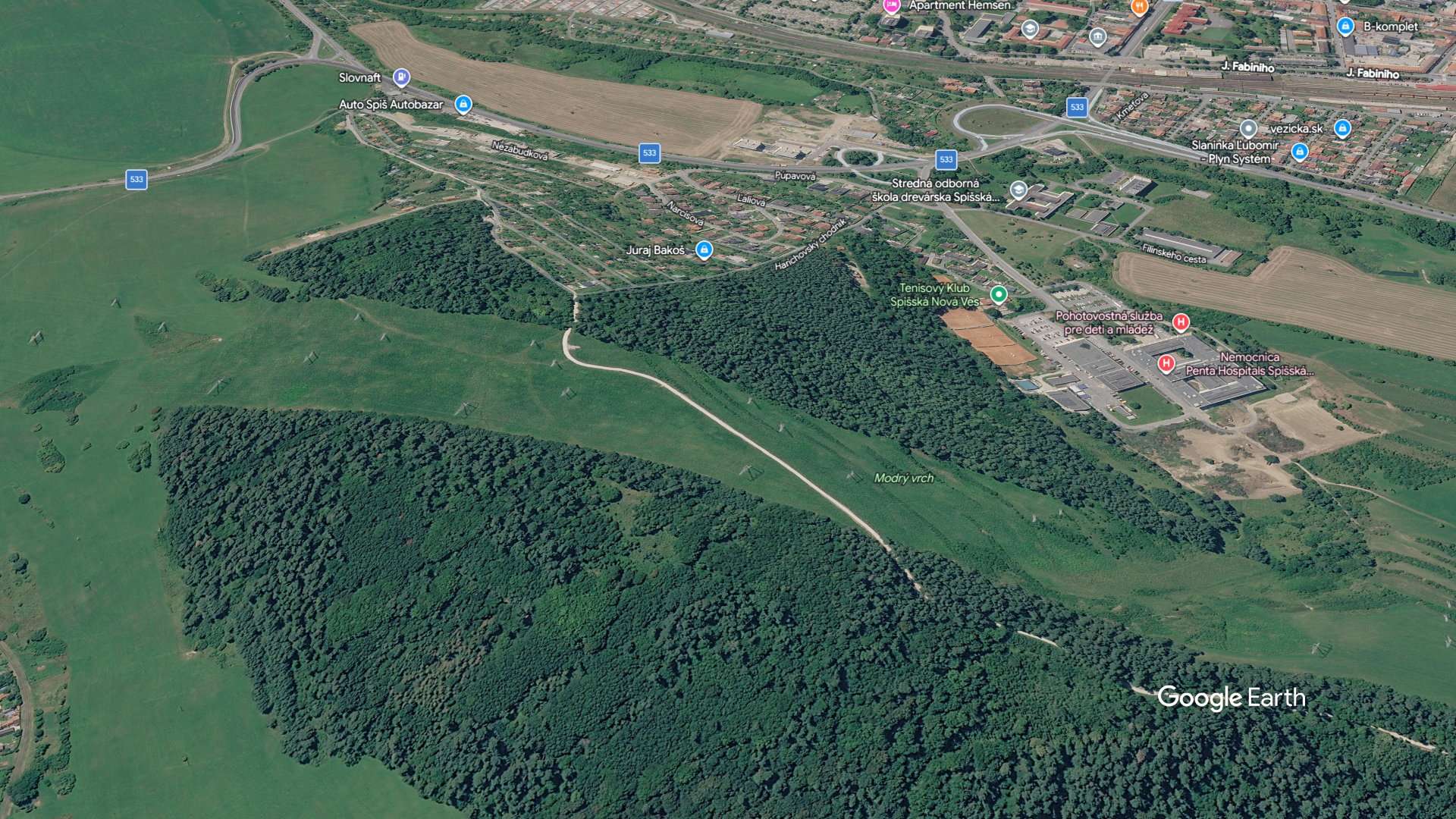 Letecký pohľad na zalesnenú lokalitu Modrý vrch v Spišskej Novej Vsi v tesnej blízkosti miestnej nemocnice a tenisových kurtov.