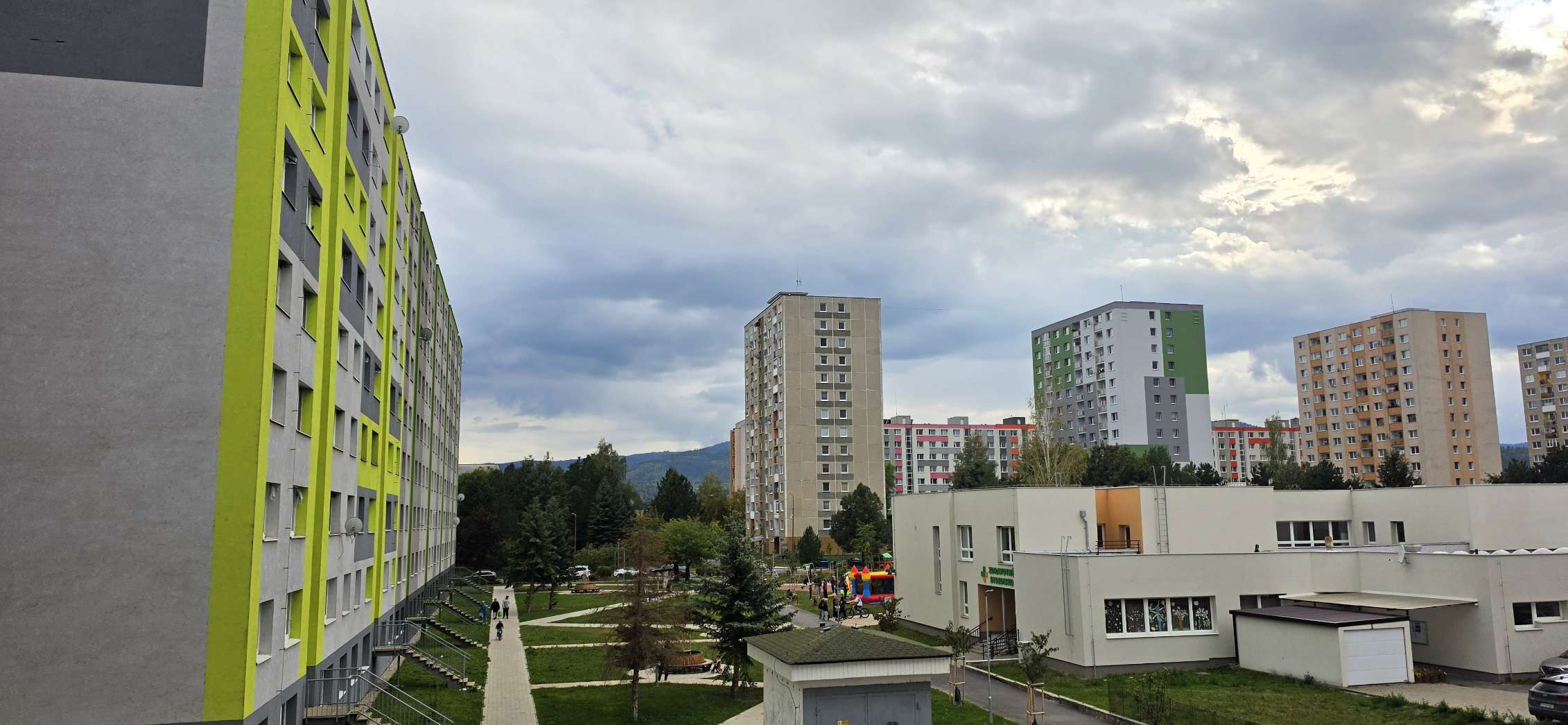 Pohľad na panelové sídlisko v Spišskej Novej Vsi, s výraznou zateplenou bytovkou v popredí pod oblačnou oblohou.